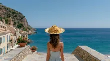 Woman standing on a Mediterranean seaside promenade overlooking the ocean, balancing a plate of pasta on her head as a surreal visual metaphor for constant thoughts about food.